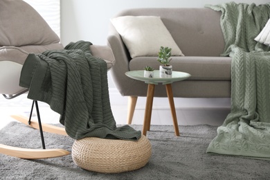 Soft knitted blanket on armchair in room. Home interior