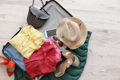 Open suitcase with clothes and accessories on floor