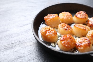 Photo of Delicious fried scallops in dish on dark gray textured table, closeup. Space for text