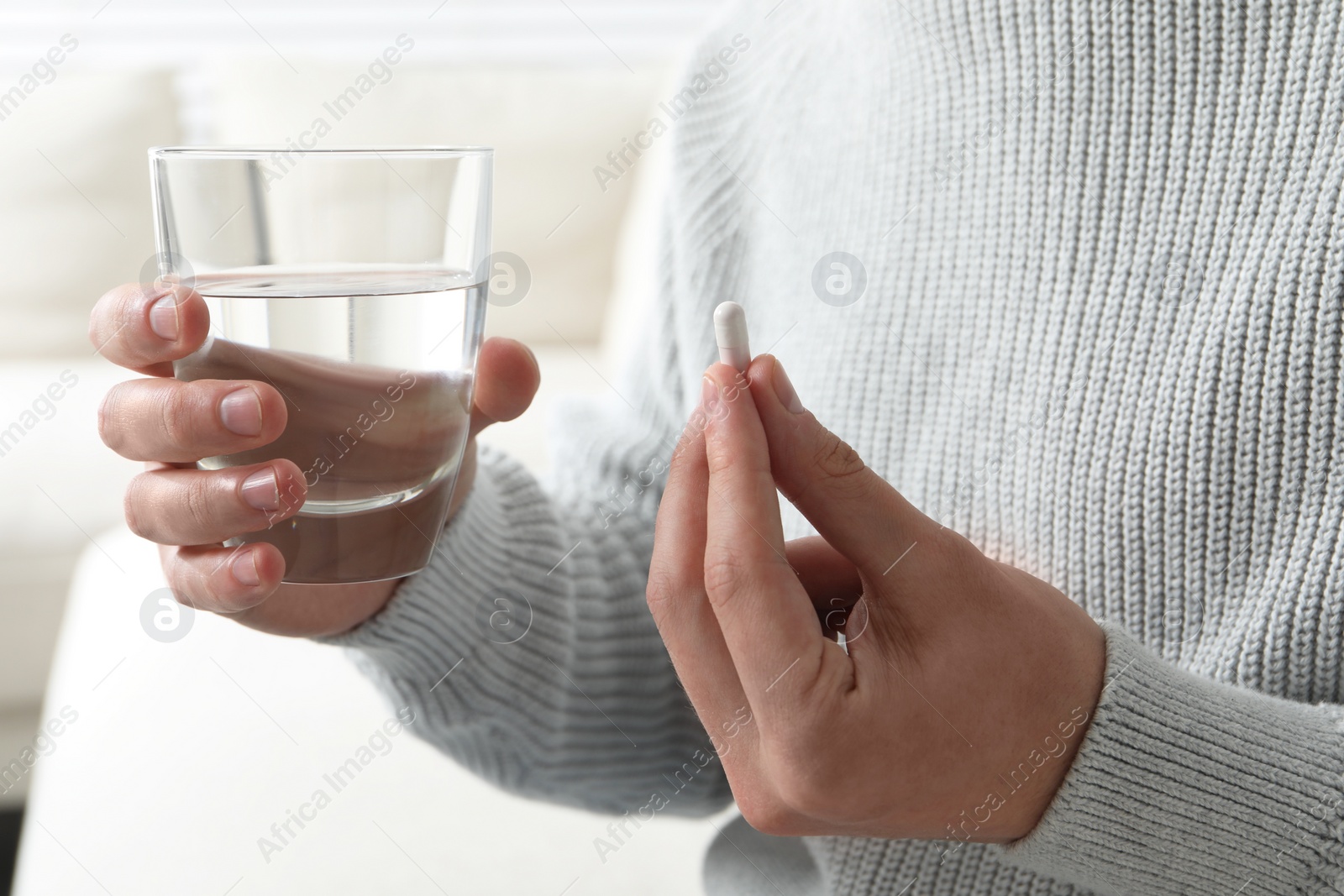 Photo of Man with glass of water and pill on blurred background, closeup