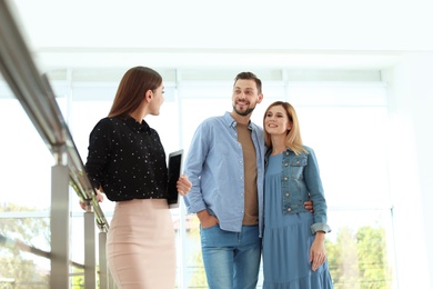 Photo of Female real estate agent showing new house to couple, indoors