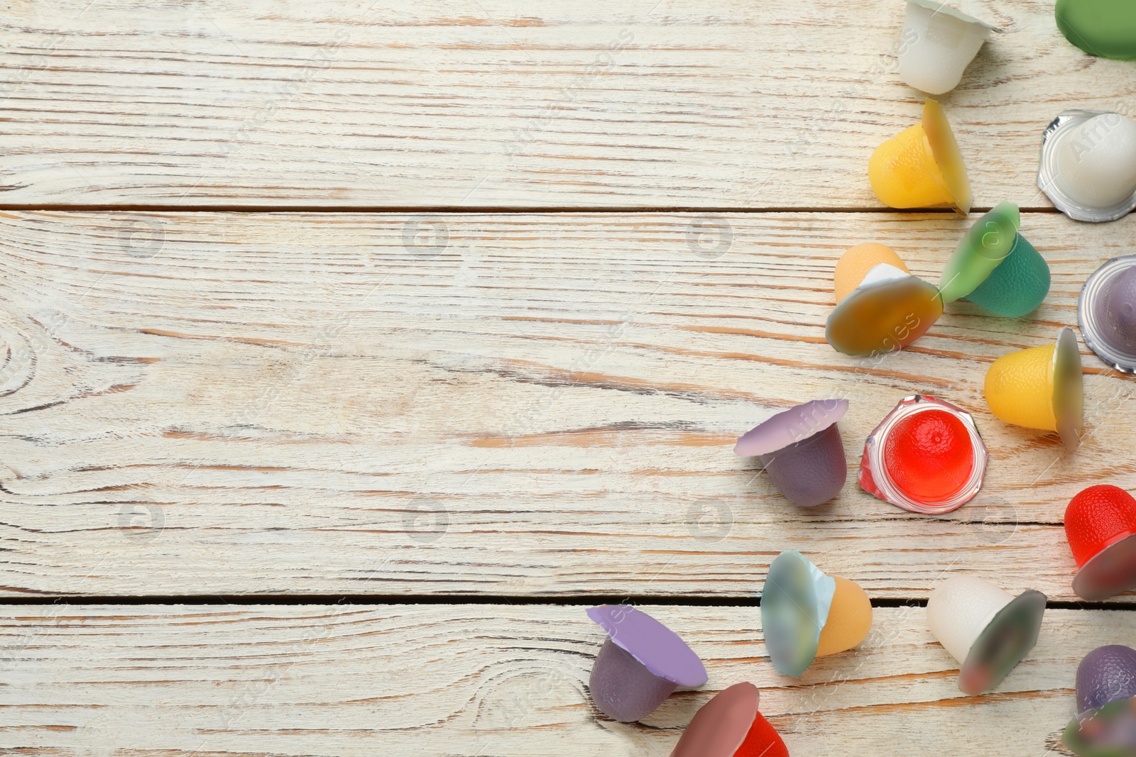 Photo of Tasty bright jelly cups on white wooden table, flat lay. Space for text