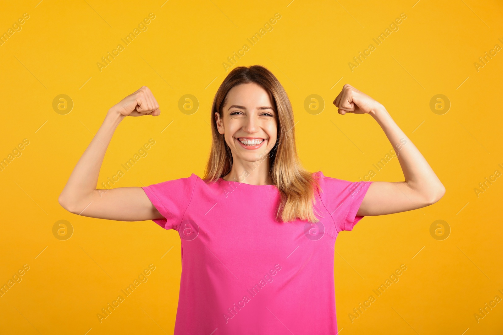 Photo of Strong woman as symbol of girl power on yellow background. 8 March concept