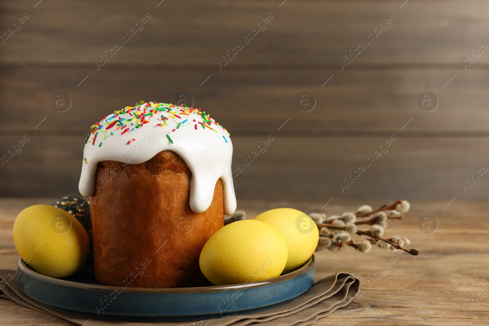 Photo of Tasty Easter cake, decorated eggs and willow branches on wooden table. Space for text