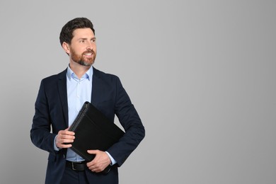 Handsome real estate agent with documents on grey background, space for text