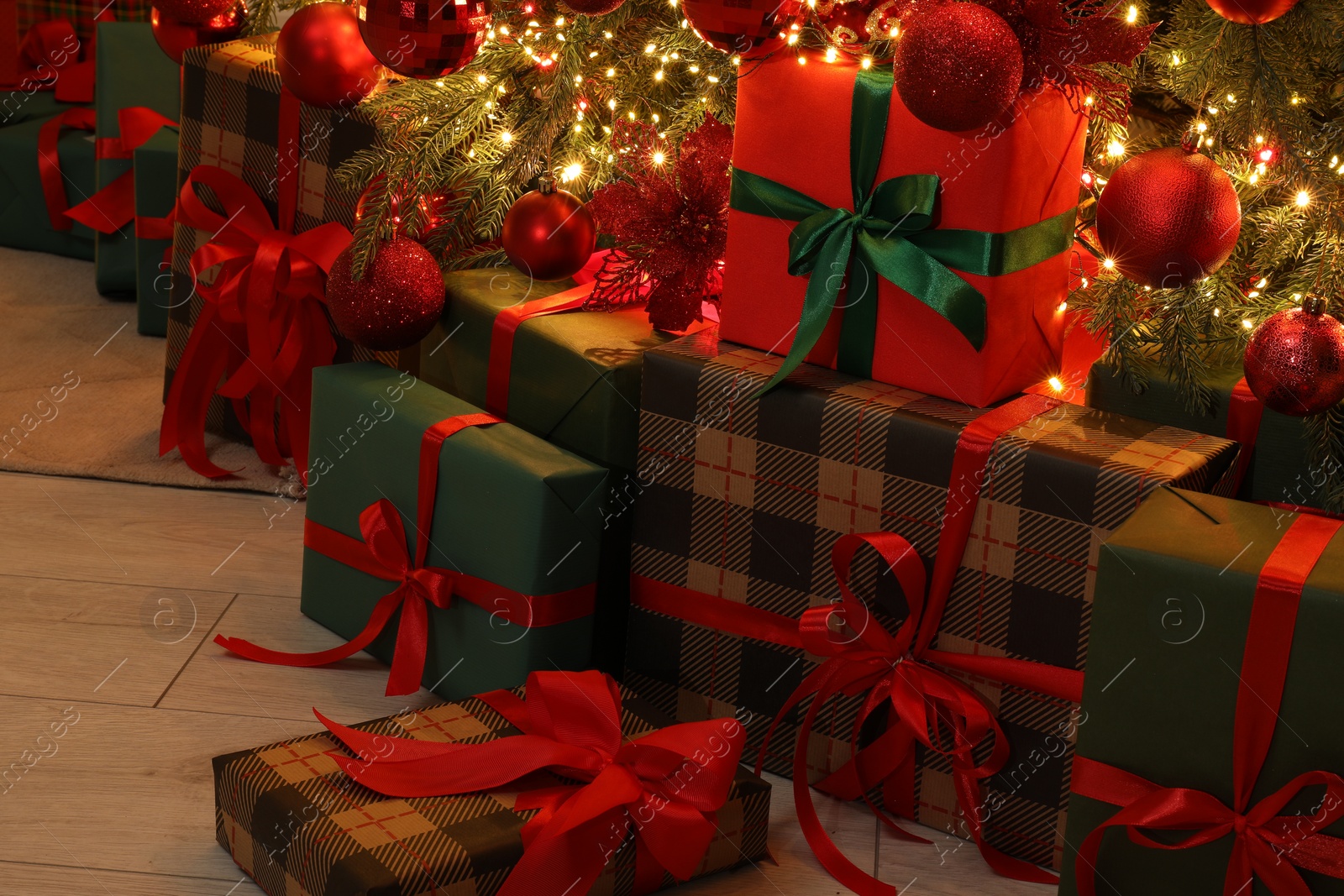 Photo of Many gift boxes under decorated Christmas tree indoors