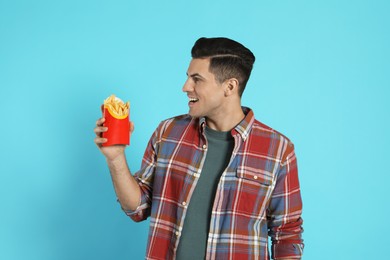 Man with French fries on light blue background