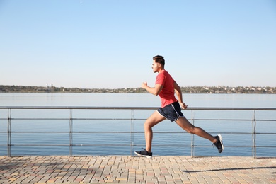 Sporty man running outdoors on sunny morning