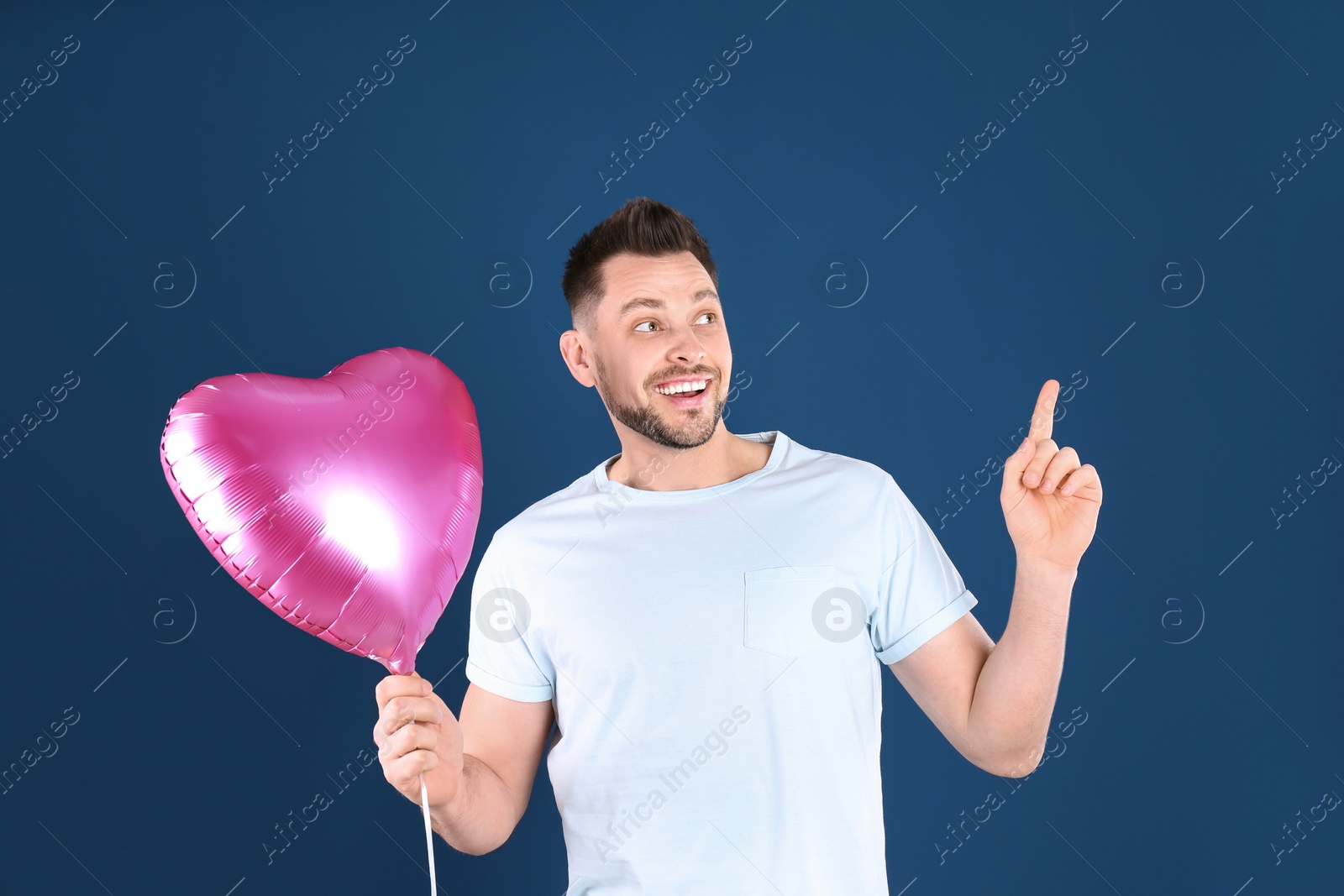 Photo of Portrait of young man with heart shaped balloon on color background