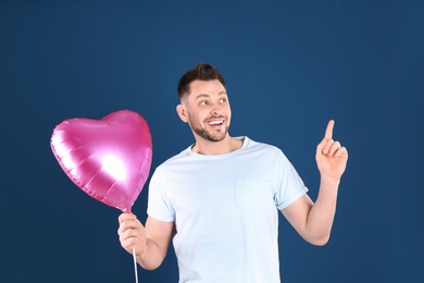 Photo of Portrait of young man with heart shaped balloon on color background