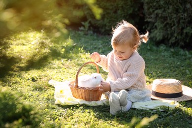 Happy little girl with cute rabbit on green grass outdoors