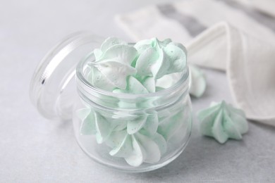 Photo of Tasty meringue cookies in glass jar on light grey table