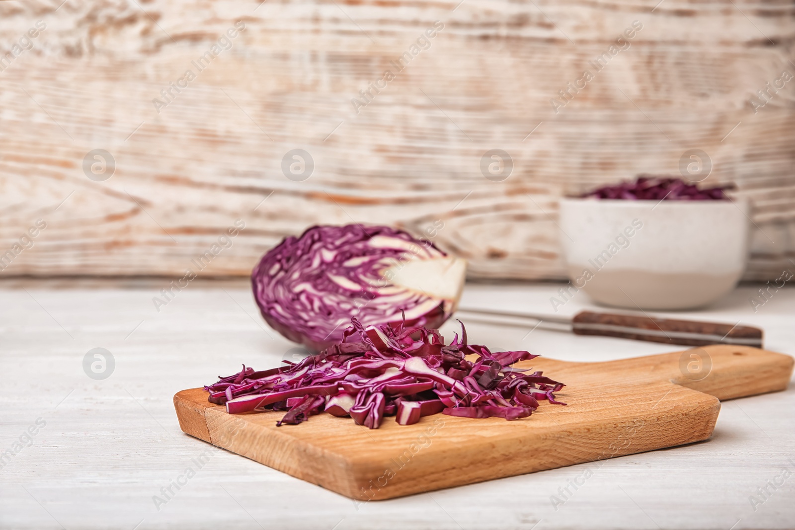 Photo of Wooden board with chopped purple cabbage on table