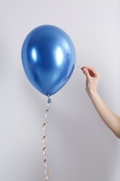 Woman piercing balloon with needle on white background, closeup