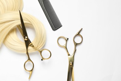 Photo of Professional hairdresser scissors and comb with blonde hair strand on white background, flat lay