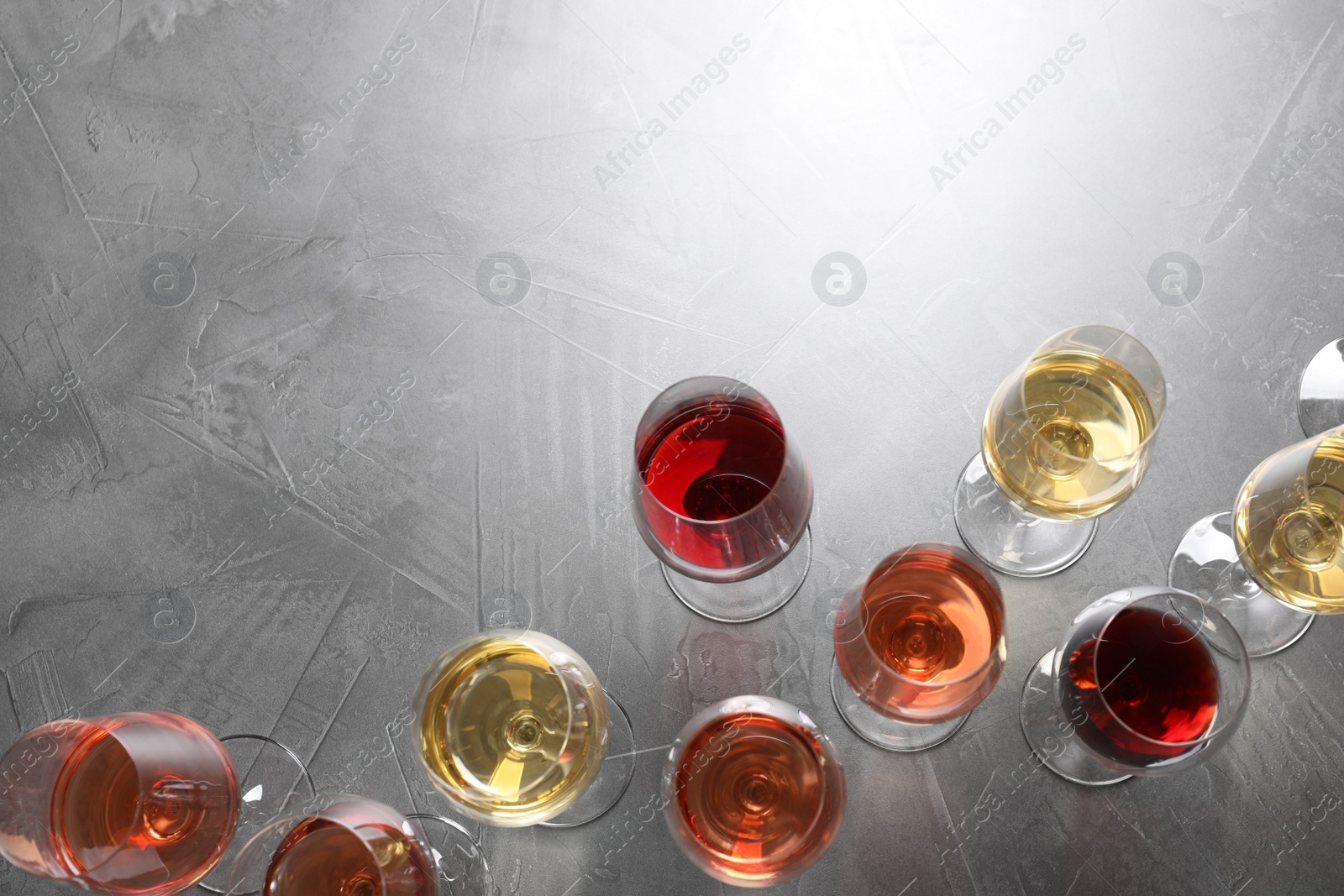 Photo of Different glasses with wine on grey background, flat lay. space for text