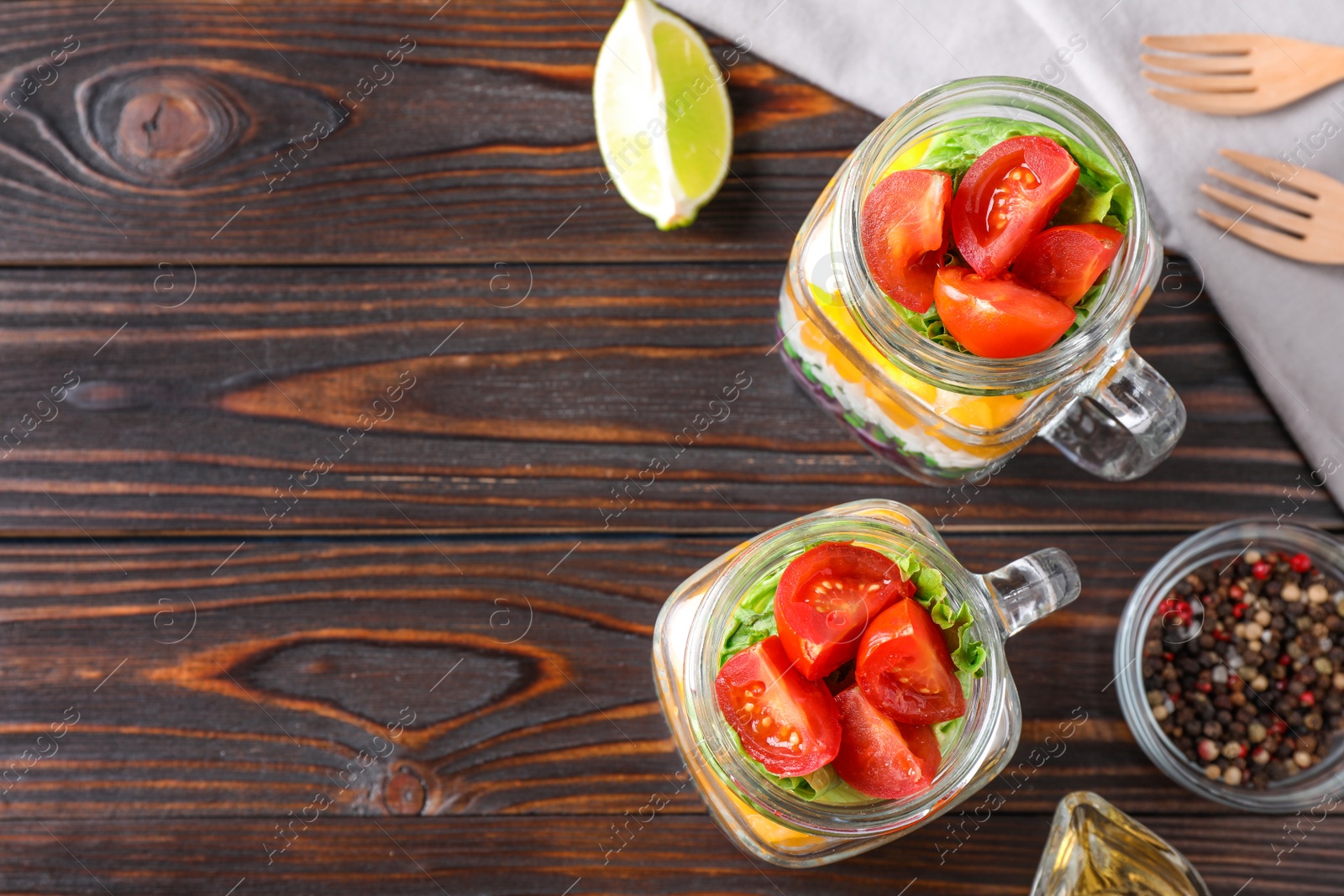 Photo of Healthy salad in glass jars on wooden table, flat lay. Space for text