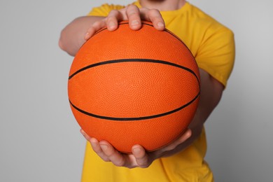 Photo of Athletic young man with basketball ball on light grey background, closeup
