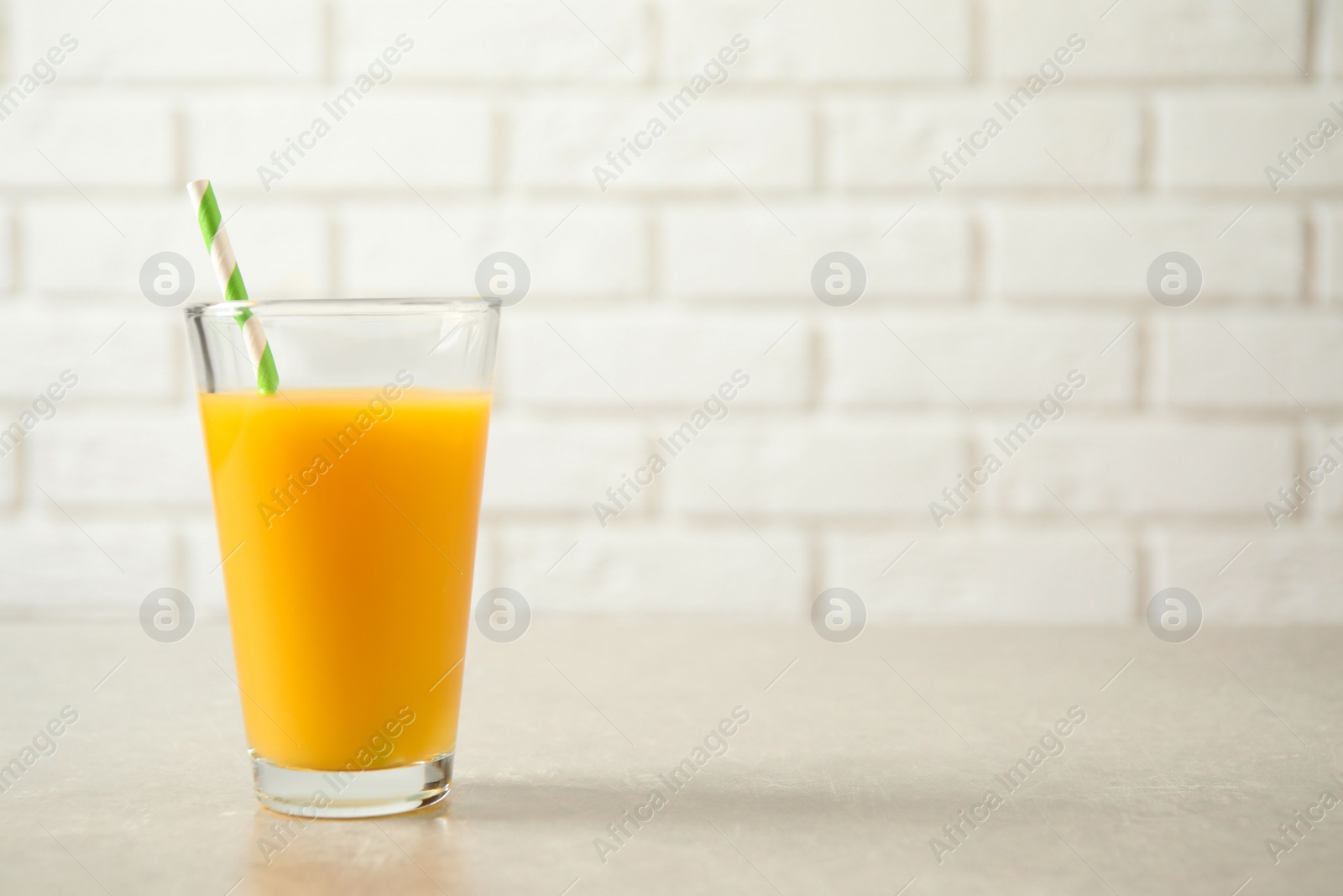 Photo of Glass of orange juice on light table. Space for text