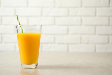 Photo of Glass of orange juice on light table. Space for text