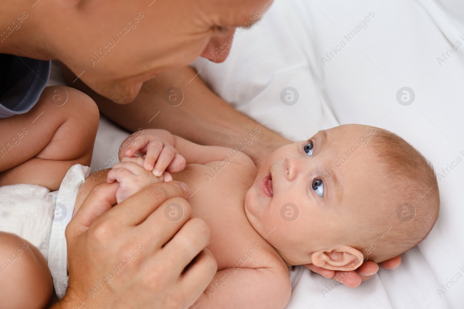 Photo of Happy father with his cute baby on bed, closeup