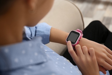 Photo of Girl using stylish smart watch on sofa indoors, closeup