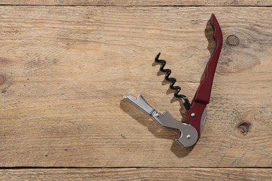 Photo of One corkscrew (sommelier knife) on wooden table, top view. Space for text