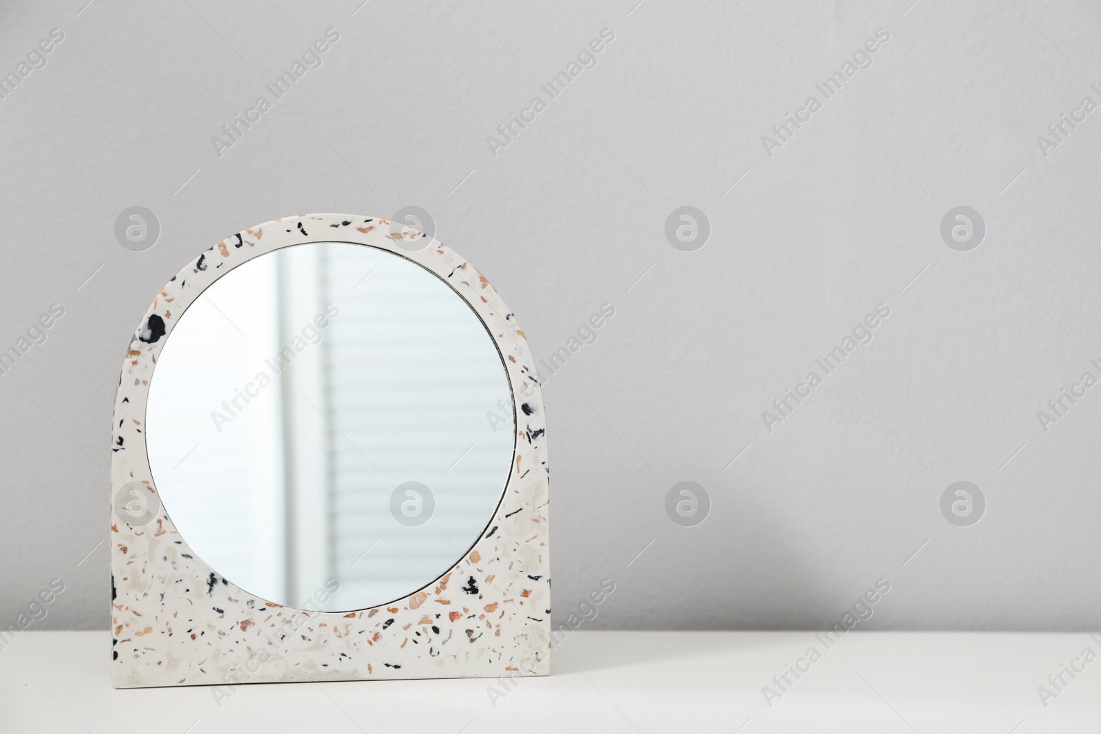 Photo of Stylish round mirror on table near white wall, space for text