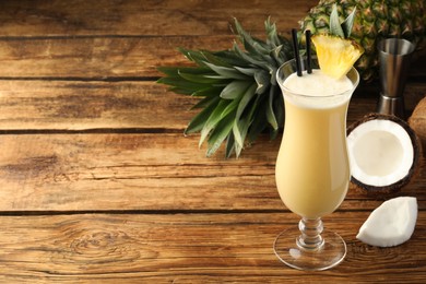 Tasty Pina Colada cocktail and ingredients on wooden table, space for text