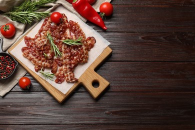 Photo of Slices of tasty fried bacon, tomatoes and different spices on wooden table, top view. Space for text