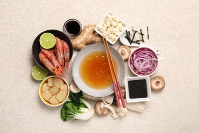 Cooking delicious ramen soup. Different fresh ingredients in bowls and chopsticks on beige table, flat lay