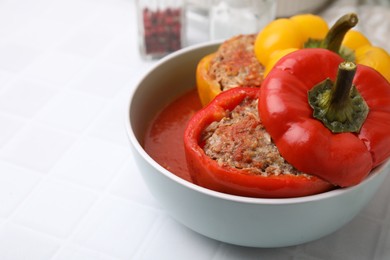 Photo of Delicious stuffed bell peppers on white tiled table, closeup. Space for text