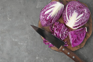 Photo of Fresh red cabbage, knife and cutting board on grey table