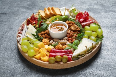 Photo of Wooden platter with different tasty appetizers on grey table