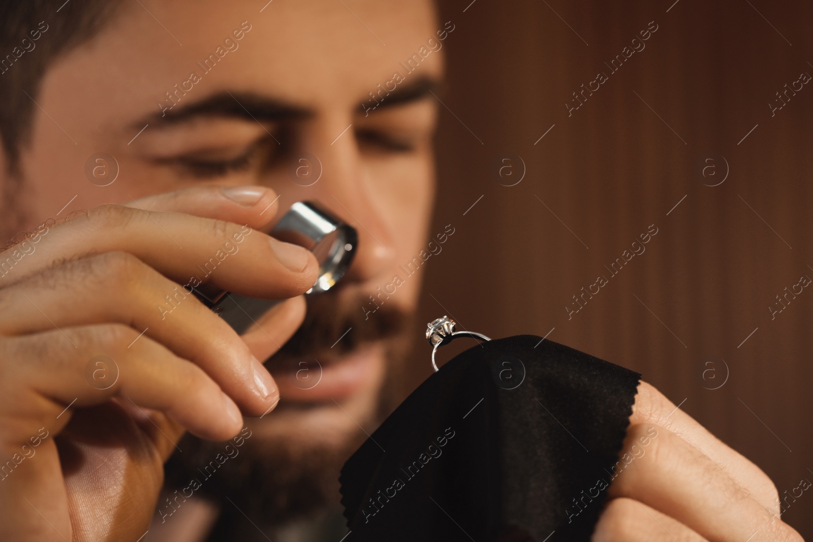 Photo of Jeweler working with ring on blurred background, closeup