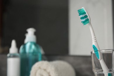 Light blue toothbrush in glass holder indoors, space for text
