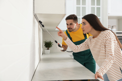 Photo of Woman showing insect traces to pest control worker in kitchen