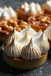 Photo of Many different tartlets on black textured table, closeup. Tasty dessert