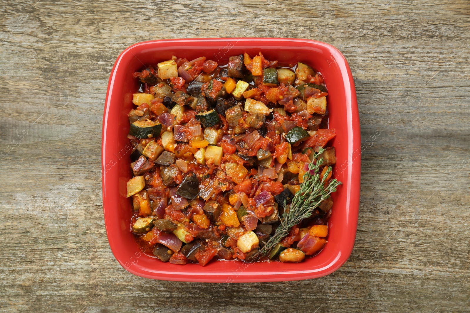 Photo of Dish with tasty ratatouille on wooden table, top view