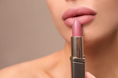 Photo of Woman with pink lipstick on brown background, closeup
