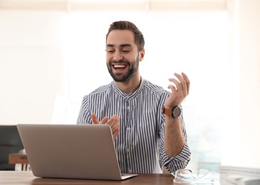 Young man using video chat on laptop in home office