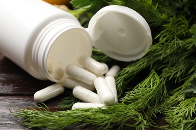 Dietary supplements. Overturned bottle, pills and dill on wooden table, closeup