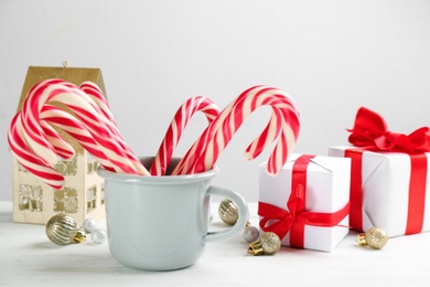 Photo of Many sweet candy canes, gift boxes and Christmas decor on white wooden table