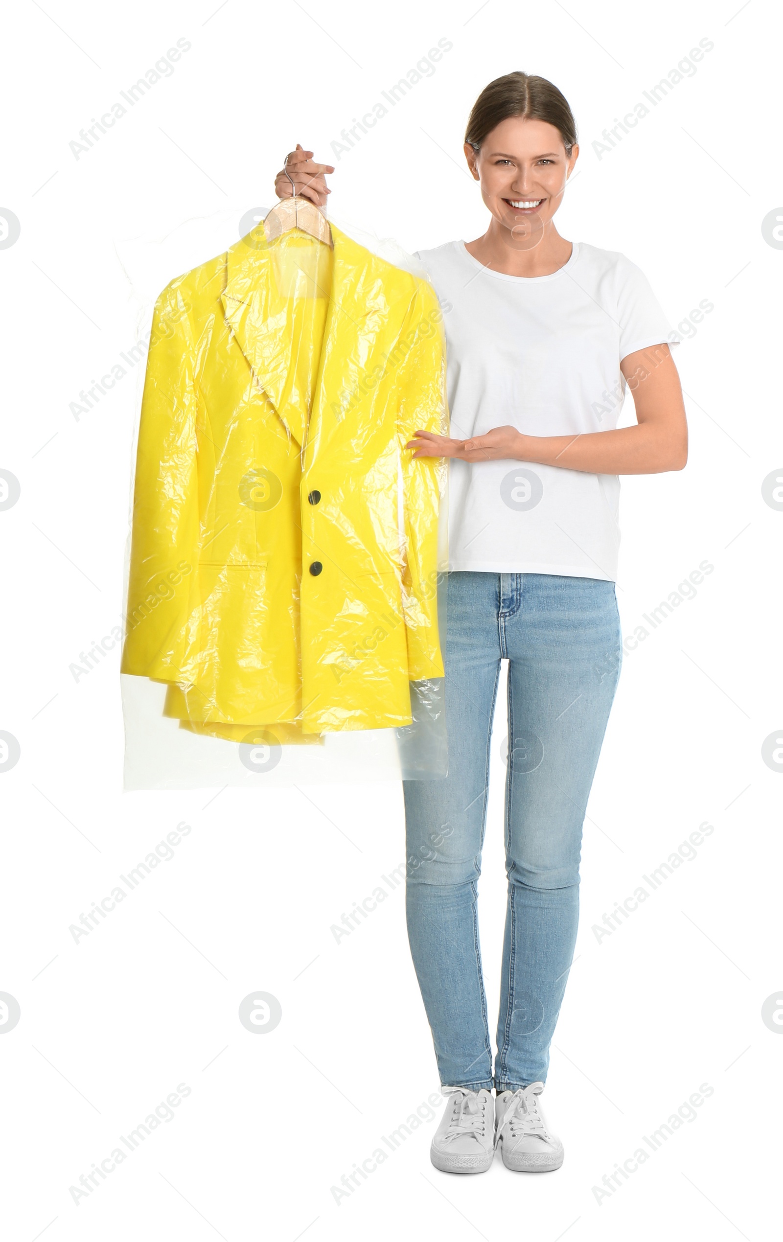 Photo of Young woman holding hanger with jacket in plastic bag on white background. Dry-cleaning service