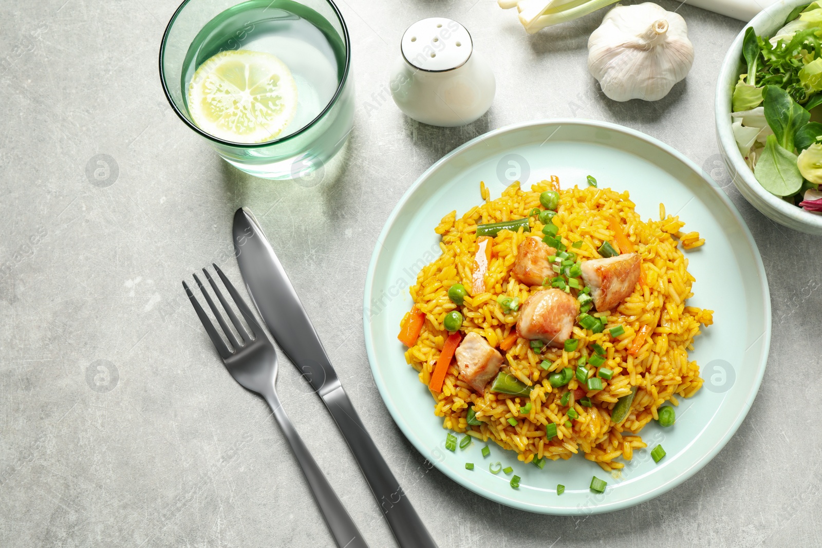 Photo of Delicious rice pilaf with vegetables and chicken served on light grey table, flat lay