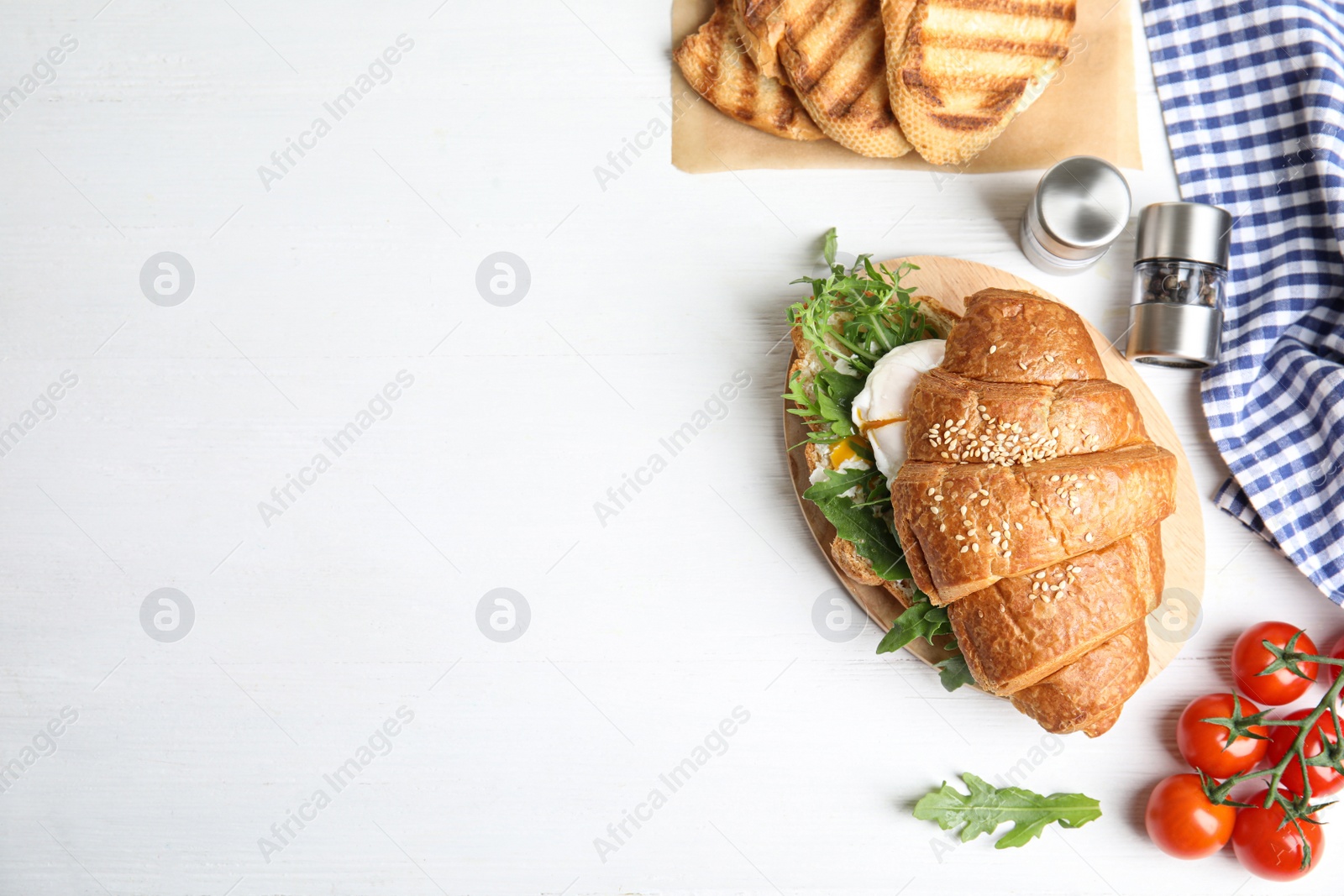 Photo of Delicious croissant with arugula and egg on white wooden table, flat lay. Space for text
