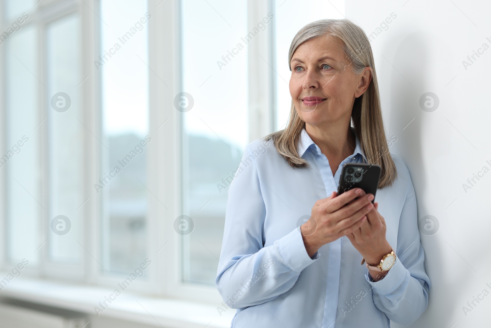 Photo of Senior woman using mobile phone at home, space for text