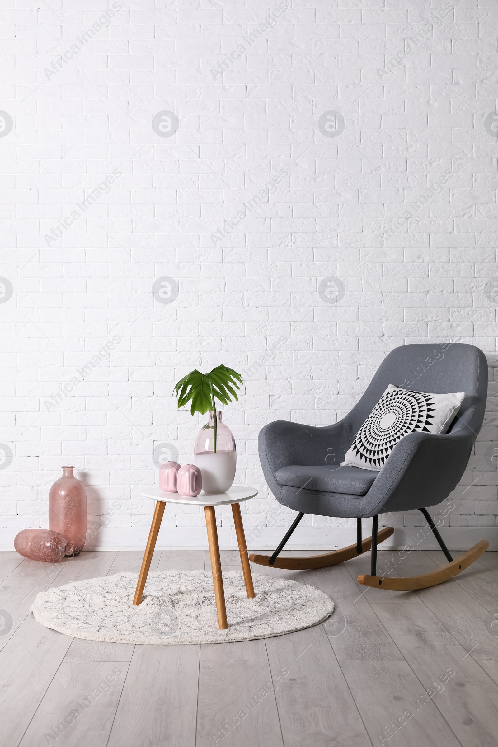 Photo of Living room interior with vases on coffee table and comfortable armchair near white wall