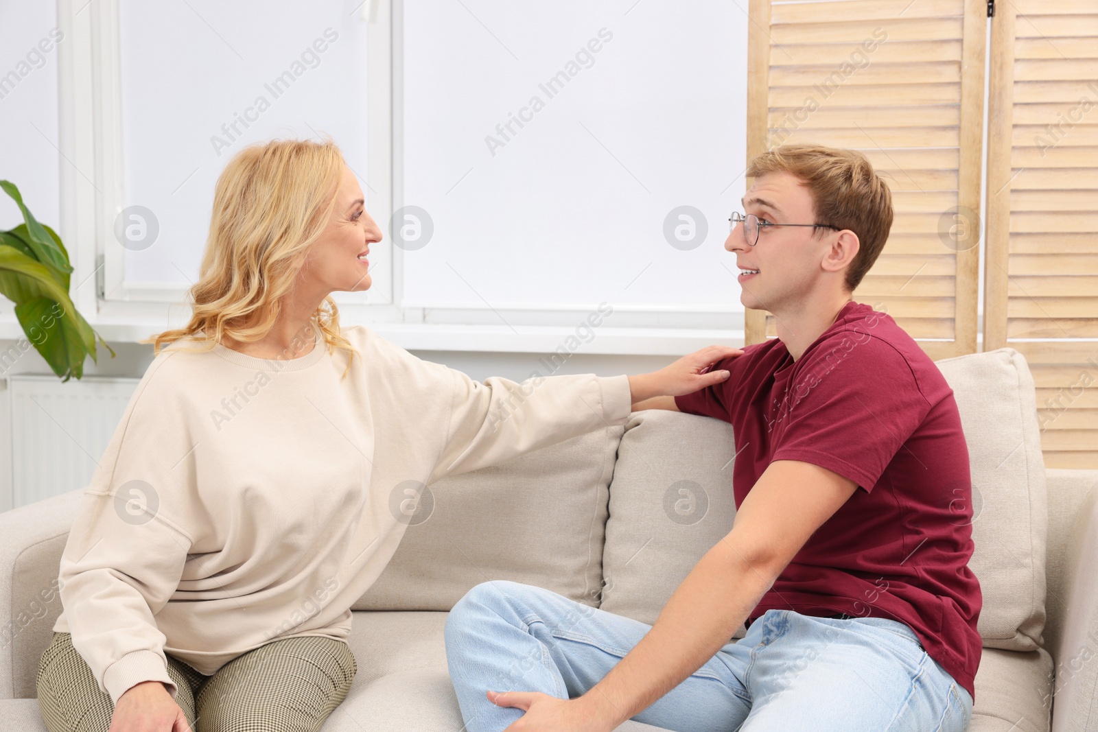 Photo of Mother and son spending time together on sofa at home. Family bonding