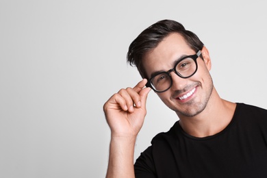 Photo of Portrait of handsome young man in black t-shirt with glasses on grey background. Space for text